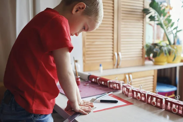 Мальчик делает искусный календарь пришествия, как горнолыжный курорт или поезд с туалетной бумаги рулоны дома — стоковое фото