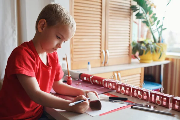 Boy gör skapad adventskalender som skidort eller tåg med toapapper rullar hemma — Stockfoto