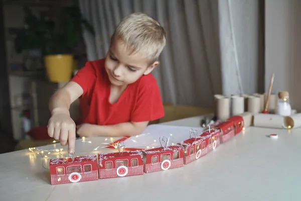 Pojke leker med skapad adventskalender som tåg eller linbana gjord med toalettpapper rullar hemma — Stockfoto