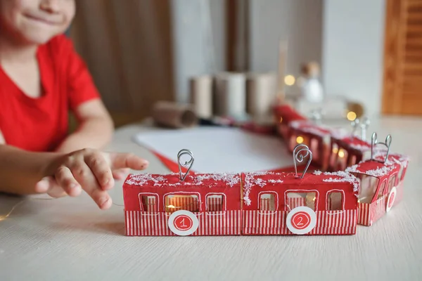 Jongen speelt met vervaardigde adventskalender zoals trein of kabelbaan gemaakt met wc-papier rollen thuis — Stockfoto