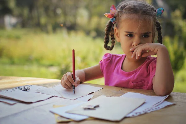 Concetto retrò e vintage. Una ragazzina che scrive una lettera con penna a inchiostro, vecchie buste — Foto Stock