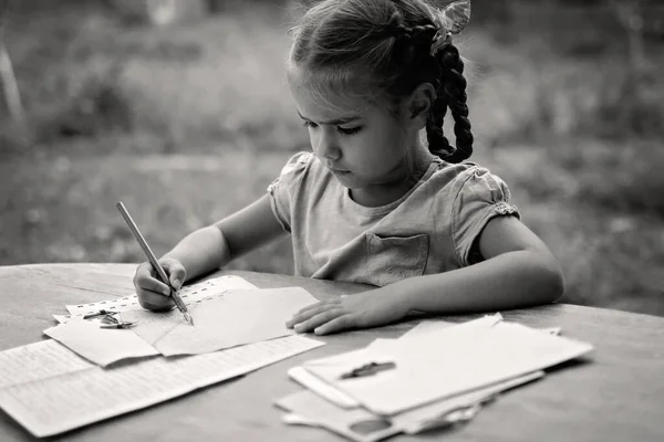 Retro and vintage concept. A little girl writing a letter with ink pen, old envelopes — Stock Photo, Image