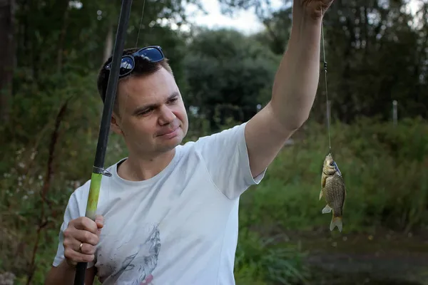 Homme adulte attrapant un poisson sur le lac — Photo