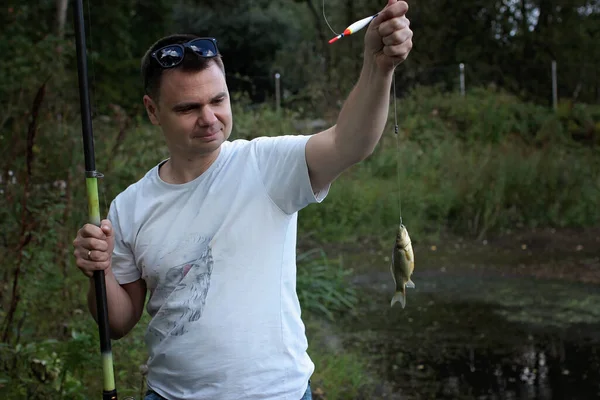 L'uomo adulto cattura un pesce sul lago — Foto Stock