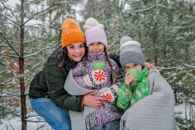 Mutlu çocuklar kış pikniği sırasında ormanda çay içerler. Kar gününde, heyecanlı aile yürüyüşü.