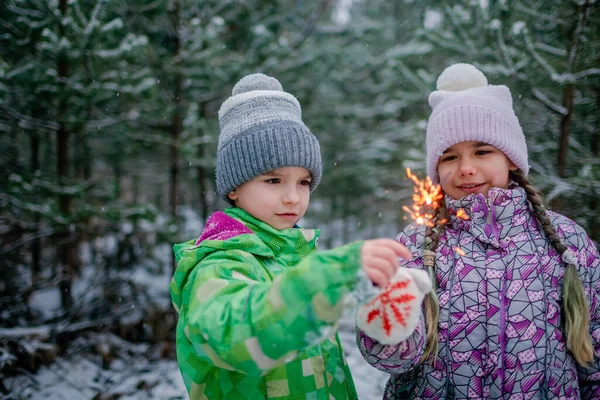 Szczęśliwa rodzina z płonącymi ogniami podczas spaceru po lesie w śnieżny dzień, Boże Narodzenie — Zdjęcie stockowe