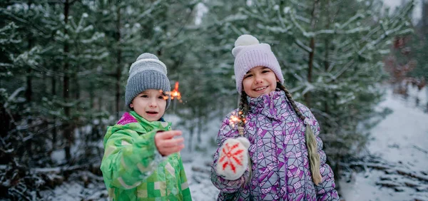 Lycklig familj med brinnande tomtebloss under vandringen i skogen på snön dag, julfirande — Stockfoto