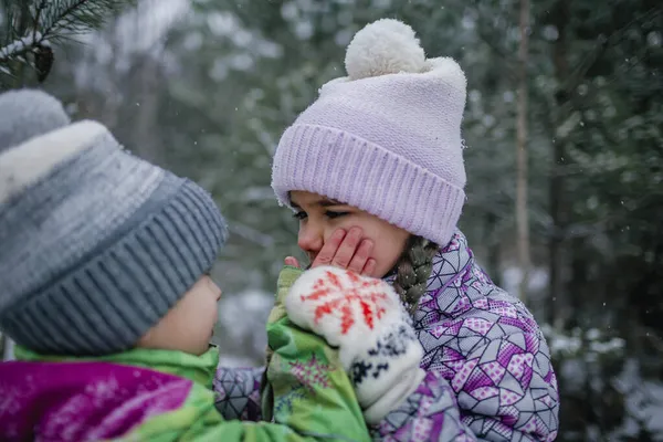 Flicka andas på frysta händer av sin bror att värma dem under familjen promenader i skogen på vintern — Stockfoto