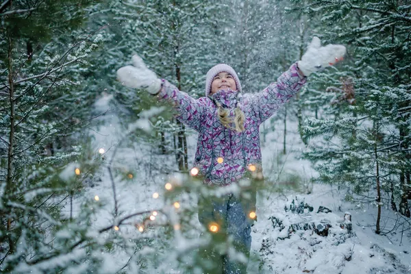 Dziewczyna cieszy się pierwszym śniegiem podczas rodzinnego spaceru po lesie w śnieżny dzień, zimowa kraina czarów — Zdjęcie stockowe