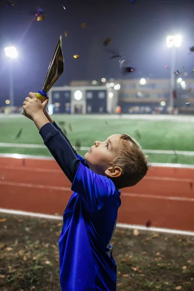 Jeune footballeur en maillot bleu avec dix numéros tenant une coupe des vainqueurs après le but gagnant — Photo