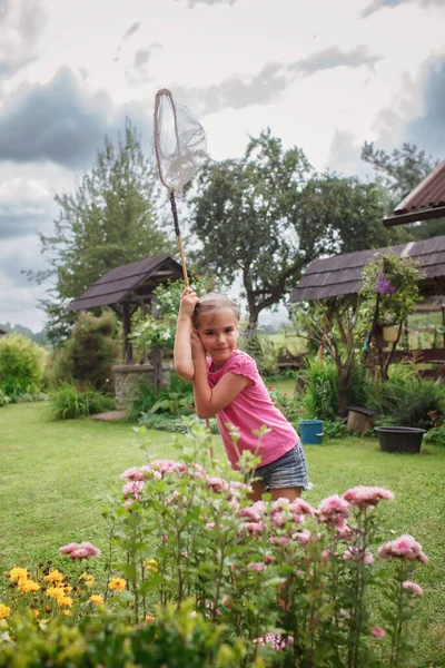Lány fogások pillangó a falu kertjében nyáron, fiatal bug-vadász, boldog nyaralást vidéken — Stock Fotó