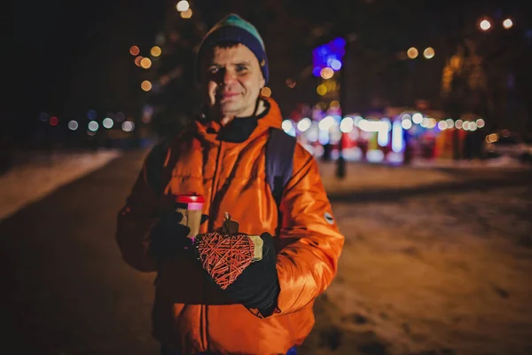 Middle aged man holds a gift with heart to give to his love partner at Valentine Day in winter city — стокове фото