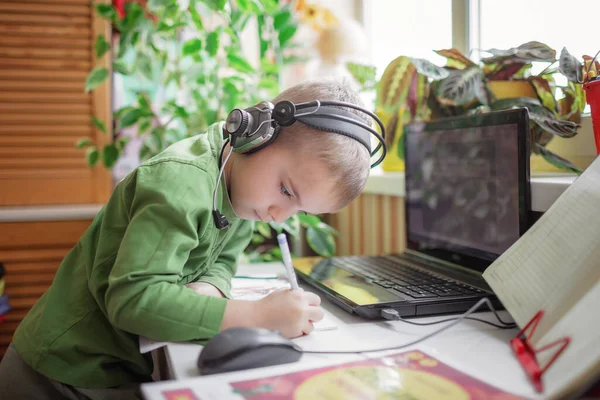 Дистанционное образование. Милый школьник, изучающий домашнее задание во время онлайн-урока дома, социальная дистанция — стоковое фото