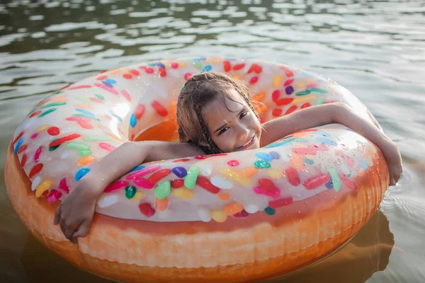 Девочка плавает с большим надувным кольцом пончика на озере в жаркий летний день, счастливого лета, cottagecore — стоковое фото