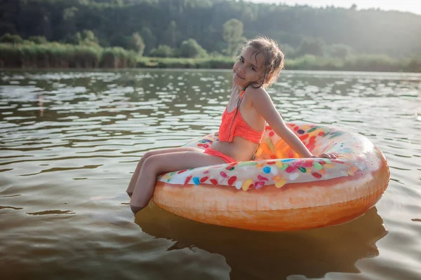 소녀는 뜨거운 여름에 호수 위에서 커다란 도넛처럼 부풀어 오르는 고리를 달고 헤엄치죠 행복 한 여름이에요 — 스톡 사진