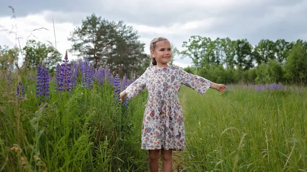 A menina corre entre os tremoços roxos no campo florescente. Saúde, natureza, verão. Infância feliz — Fotografia de Stock