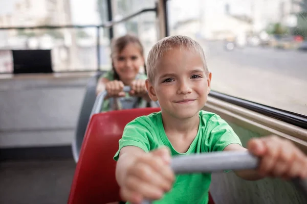 I bambini viaggiano in tram vuoto e guardano la finestra con sorriso, trasporti pubblici, tram della città — Foto Stock
