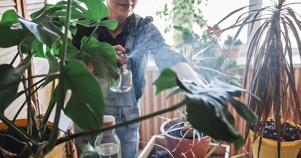 Jovem menina regando plantas em casa na varanda, ambiente verde no quarto, jardinagem em casa — Fotografia de Stock