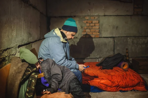 Український батько з дітьми сидить у бомбосховищі і читає останні тривожні новини про російських загарбників. — стокове фото
