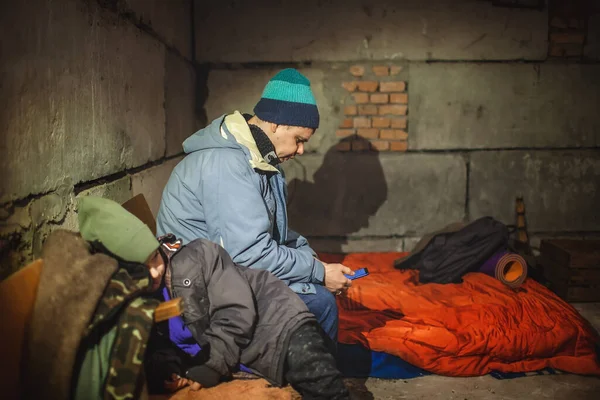 Украинский отец с детьми сидит в бомбоубежище и читает последние новости о русских захватчиках — стоковое фото