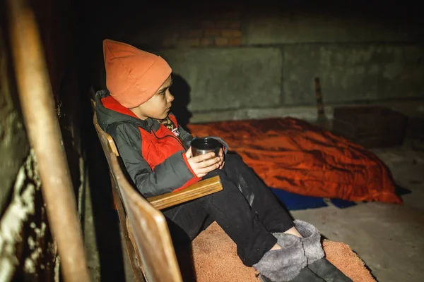 Ukrajinská dívka sedí v krytu bomby, pije čaj a čeká na konec náletu ruských vetřelců — Stock fotografie