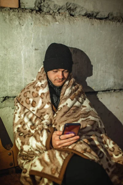 Un tânăr ucrainean se află într-un adăpost pentru bombe și citește cele mai recente știri despre invadatorii ruși — Fotografie, imagine de stoc
