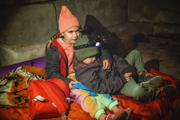 Kids with Ukrainian flag lay in bomb shelter and waits for end of airstrike of Russian invaders — Stock Photo, Image