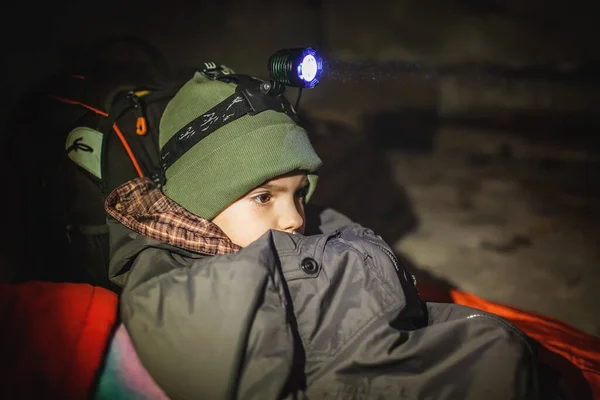 Ukrainian boy with headlamp lay in bomb shelter and waits for end of airstrike of Russian invaders — Stock Photo, Image