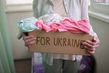 Kadın, Rus istilasından muzdarip Ukrayna vatandaşları için insani yardım dolu bir kutu tutuyor.