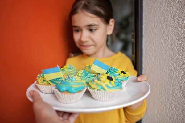 Ukrán lány, akinek a szomszédok hozott cupcakes krémmel sárga és kék színű villásreggeli — Stock Fotó