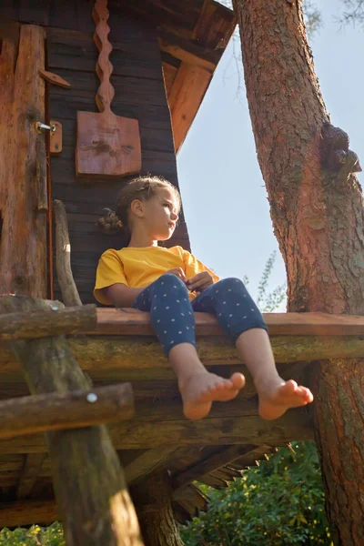 Chica juega en creativa casa del árbol hecho a mano en el patio trasero, actividad de verano, infancia feliz, cottagecore — Foto de Stock