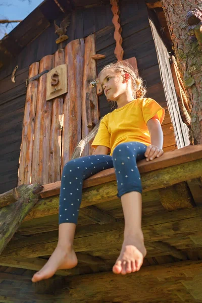 Chica juega en creativa casa del árbol hecho a mano en el patio trasero, actividad de verano, infancia feliz, cottagecore — Foto de Stock