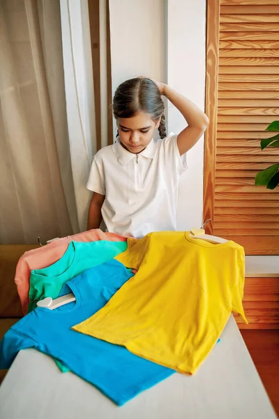 Девушка выбирает футболку из одежды дома. Модель дружелюбная. Футболки готовы к дизайну — стоковое фото