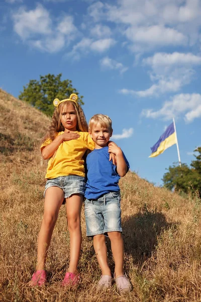 在乌克兰最大的国旗附近，穿黄色衣服的女孩和穿蓝色衣服的男孩。为和平与胜利祈祷 — 图库照片
