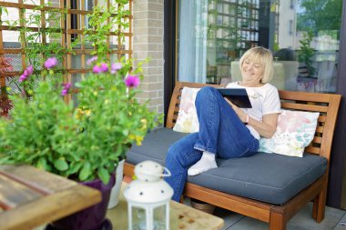 Üst düzey kadın arkadaşlarıyla evdeki balkondaki tablet aracılığıyla konuşuyor. Aktif bebek patlama nesli