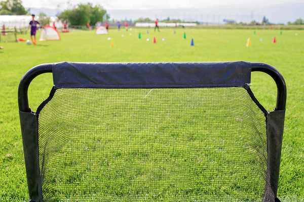 绿草上的足球齿轮准备在儿童足球学院接受训练。流行体育活动 — 图库照片