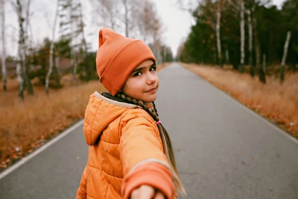 Happy Girl Orange Coat Hat Stretches Out Hand Invite Share — стоковое фото