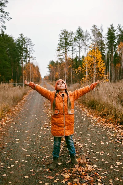 Pensive Ten Years Girl Orange Coat Outstretched Arms Enjoys Fresh — стоковое фото