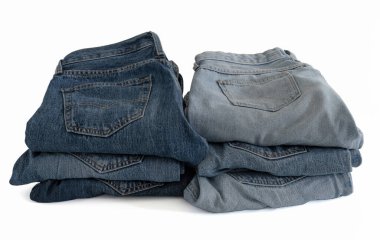 Geri dönüşümlü pamuktan yapılmış kotlar beyaz arka plandaki bir dükkandaki gibi istiflenir.