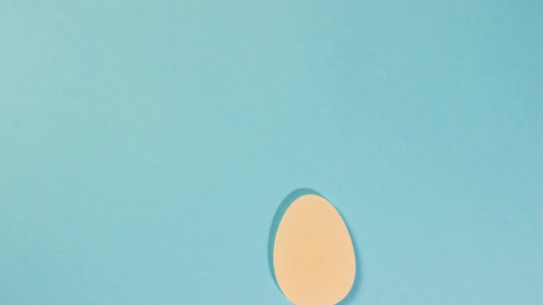 Feliz Pascua. Los huevos multicolores se mueven sobre un fondo azul. Dos conejos blancos saltan al final. Detener animación en movimiento. — Vídeo de stock