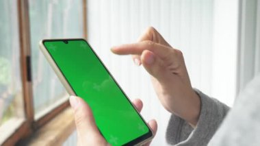 Bir kadının eli, ekranında kroma anahtarı olan bir cep telefonu tutar. Bir kadın telefonunu kaydırıyor. Yüksek kalite 4k görüntü
