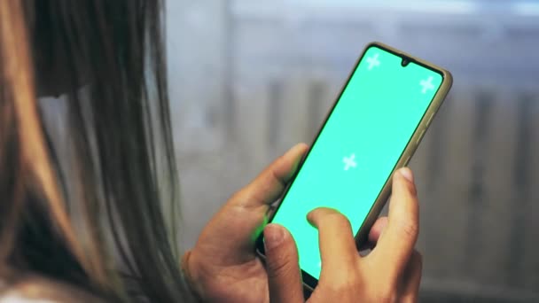 Kahverengi Saçlı Bir Kız Elinde Yeşil Arka Planlı Bir Telefon — Stok video
