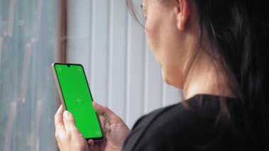 Bir kadının eli, ekranında kroma anahtarı olan bir cep telefonu tutar. Bir kadın telefonunu kaydırıyor. Yüksek kalite 4k görüntü