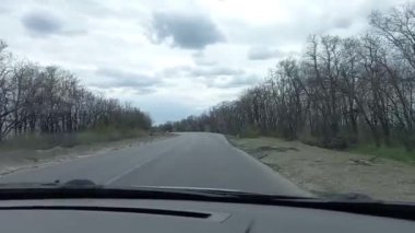 Koyu gri bir araba sıkıyönetim sırasında Ukrayna 'da bir yola giriyor. Yan ayna, anti-tank kirpileri, lastikler ve trafik konilerini gösteriyor. Yüksek kaliteli FullHD görüntüler