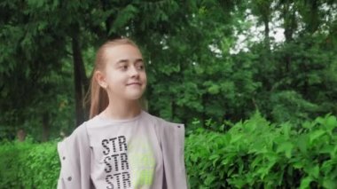 Parkta güzel bir kız yürüyor. Gülümseyen bir genç yeşil ağaçların arasında yürüyor, doğanın tadını çıkarıyor. Yüksek kalite 4k görüntü