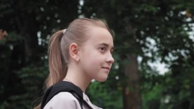 Parkta duran güzel bir kızın portresi. Saçları at kuyruklu bir kız doğanın güzelliğinden zevk alır. Yüksek kalite 4k görüntü