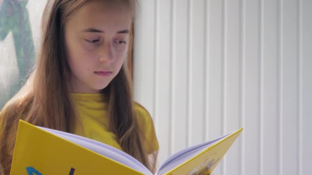 Cute Teenage Girl Long Blond Hair Yellow Shirt Reading Yellow — Vídeos de Stock