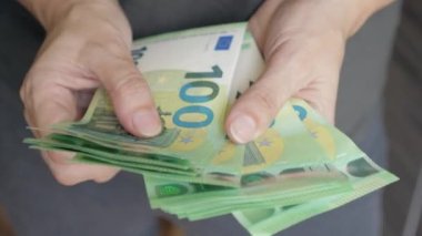 100 Euro 'luk banknotlarla kadın eli, bir yığın para sayıyor. Bir kadın vantilatöre para saçar. Yüksek kalite 4k görüntü