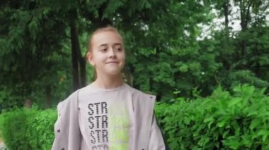 Parkta güzel bir kız yürüyor. Gülümseyen bir genç yeşil ağaçların arasında yürüyor, doğanın tadını çıkarıyor. Yüksek kalite 4k görüntü