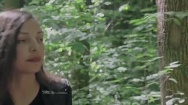 Güzel genç bir kadın ormanda tek başına yürüyor. Gün ışığı dalların arasından parlıyor. Kamera ileri gidiyor. Yüksek kaliteli FullHD görüntüler